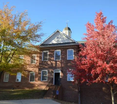 Photo of one of the buildings at James Madison University (JMU) during the Fall with beautiful trees around it