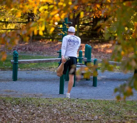 Man stretching and getting ready for a run with Fall trees overhead